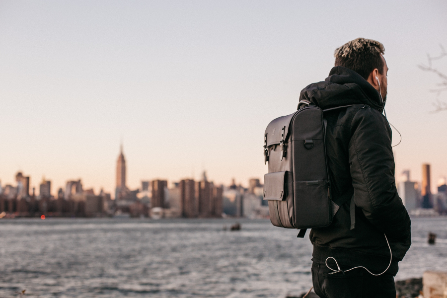 Man looking at the horizon with a nice scenary, showcasing his backpack.